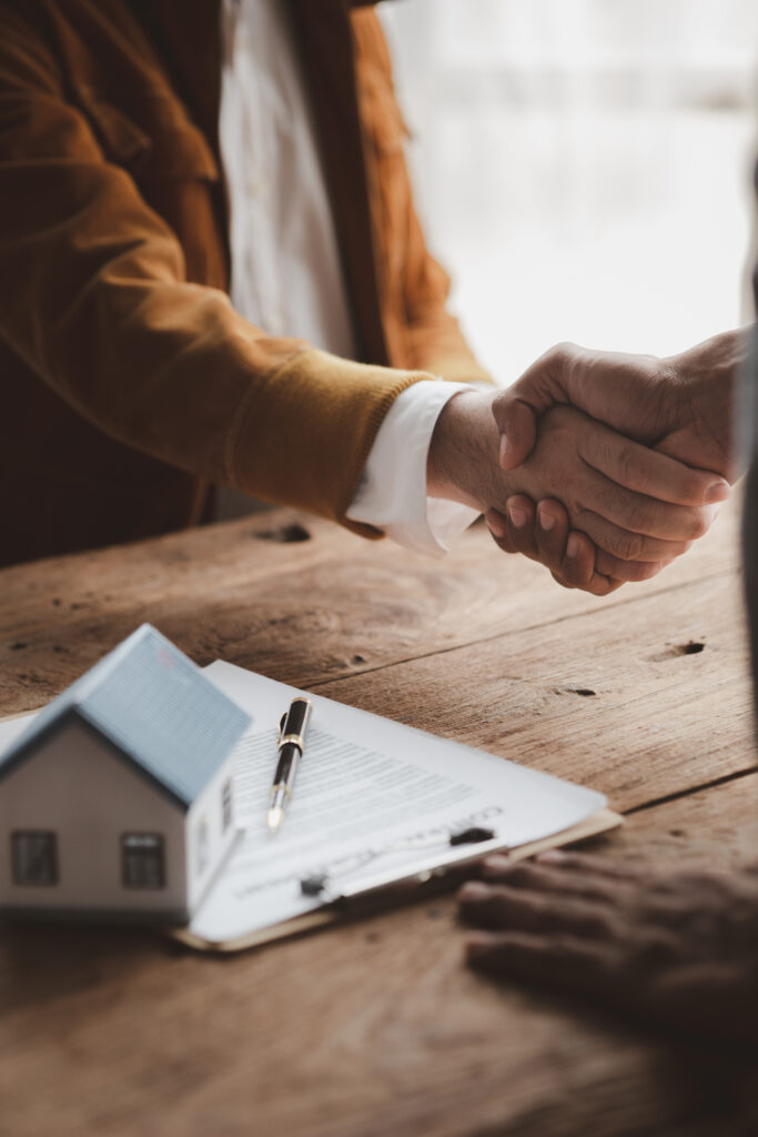 Real estate sales agents shake hands with customers of housing projects, explaining and presenting information about homes and purchasing loans. Real estate trading concept.